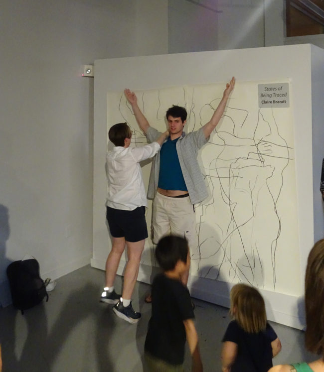 artist tracing outline of young man in performance art